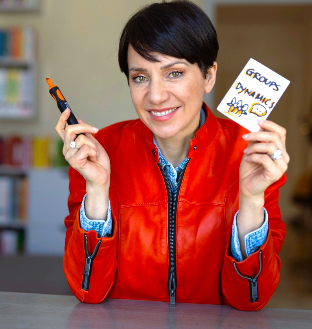 federica tabone con un giubotto rosso. In mano ha un pennarello rosso e nell'altra un foglietto con scritto groups dynamics